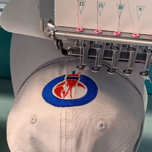 Embroidery machine stitching design on cap.